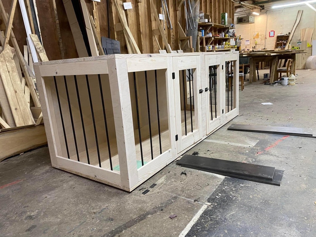Stylish dog kennels and crates made of wood with black bars in a workshop setting.