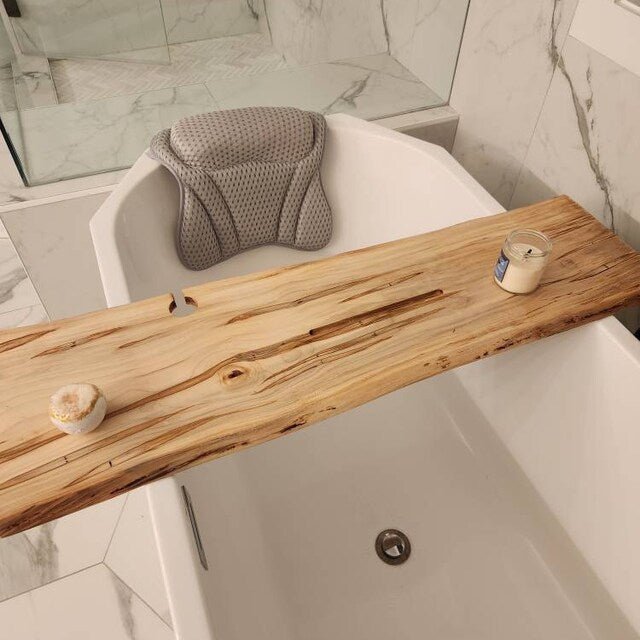 Handcrafted wood bath trays for natural bathroom luxury with a candle and a pastry on a tub.