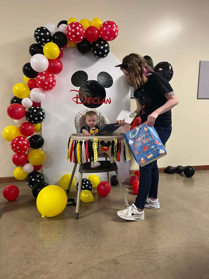 A child celebrates a milestone with the 6th custom event backdrop panel featuring balloons and a Mickey Mouse theme.