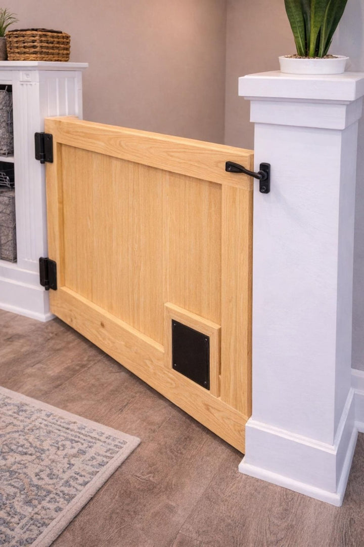 Cat passage gate with pet opening in wood finish, installed between two white pillars in a modern home.
