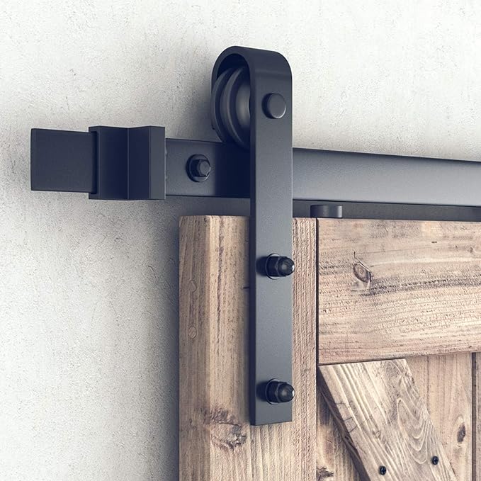 Heavy duty sliding barn door hardware with a sleek black roller mechanism attached to a wooden door.