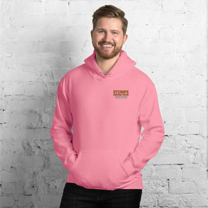Stumps Custom Wood Unisex Hoodie in pink worn by a smiling man against a brick wall.