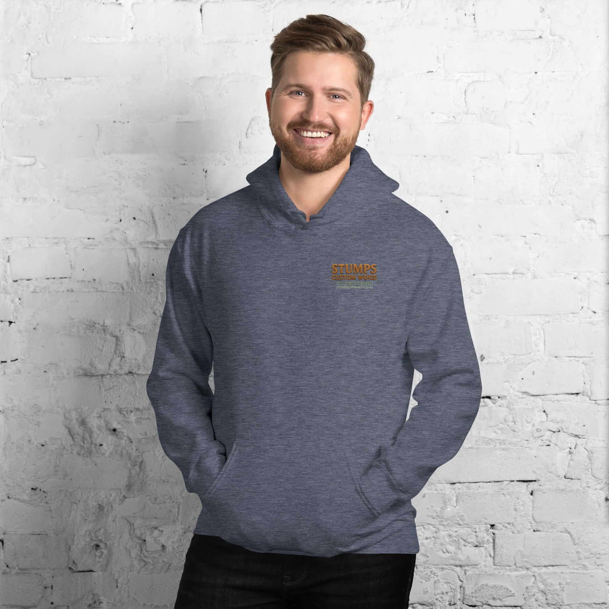 Stumps Custom Wood Unisex Hoodie displayed on a smiling man in a cozy setting with a brick wall.