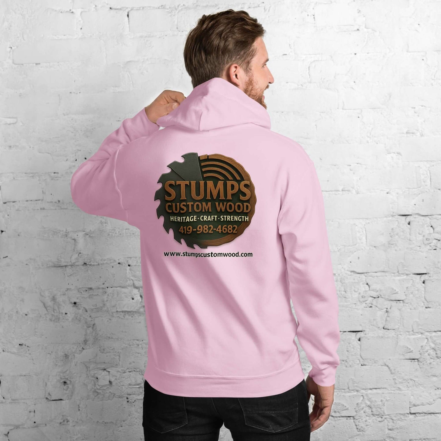 Man wearing a Stumps Custom Wood Unisex Hoodie in pink, showcasing the logo on the back.